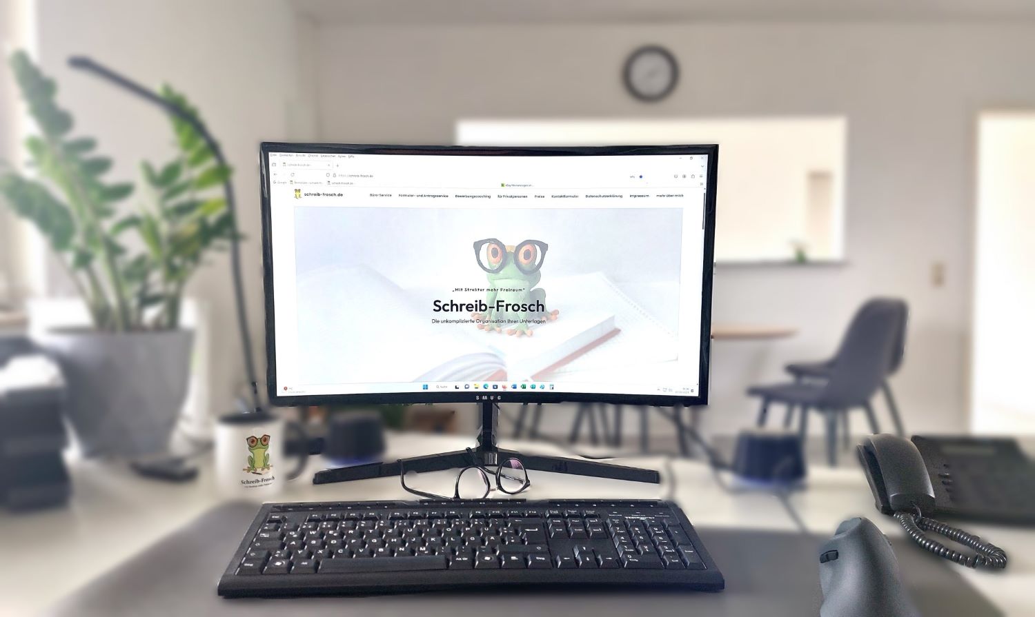 Startbildschirm der Webseite des Büroservice auf dem Schreibtisch mit Tatsatur und Pflanze im Büro Braunschweig